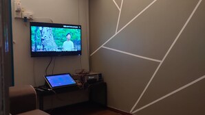 A room with a television mounted on the wall, a laptop on a small table, and a cushioned seating area. - Sea Lion Villa Stay Pulau Ketam (Pulau Ketam)