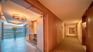 A hotel corridor with wooden walls, a patterned floor, and a view of mountains through large windows. - Holiday Inn Jilin Beidahu by IHG (Jilin)