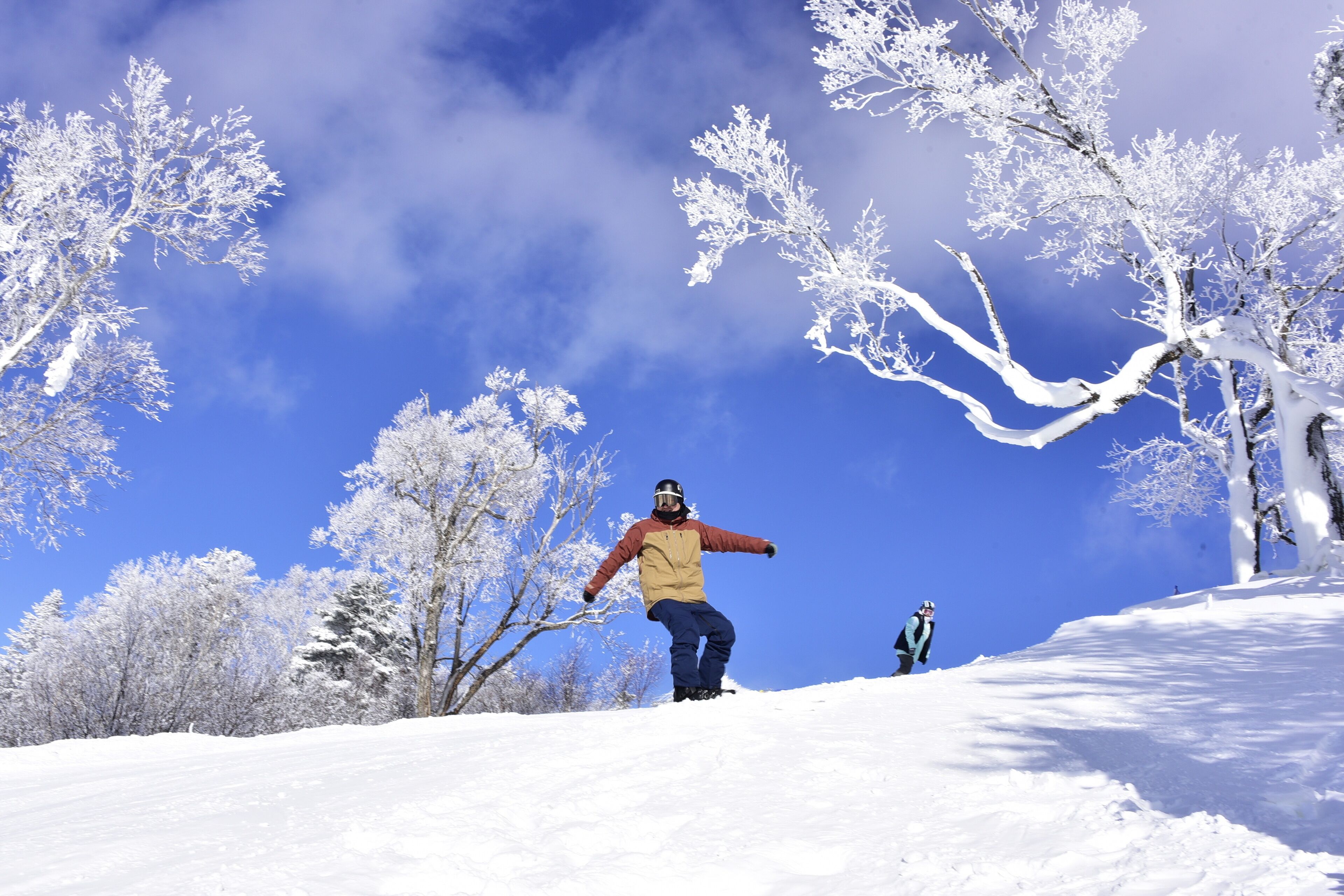 A snowy landscape with a person snowboarding.