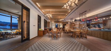 Un restaurante con mobiliario de madera, piso estampado y vistas al exterior.