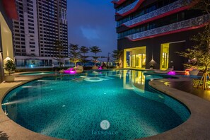 A modern hotel pool area with a circular pool, lounge chairs, and a well-lit entrance. - Arte Plus KLCC by FavSpace (Kuala Lumpur)