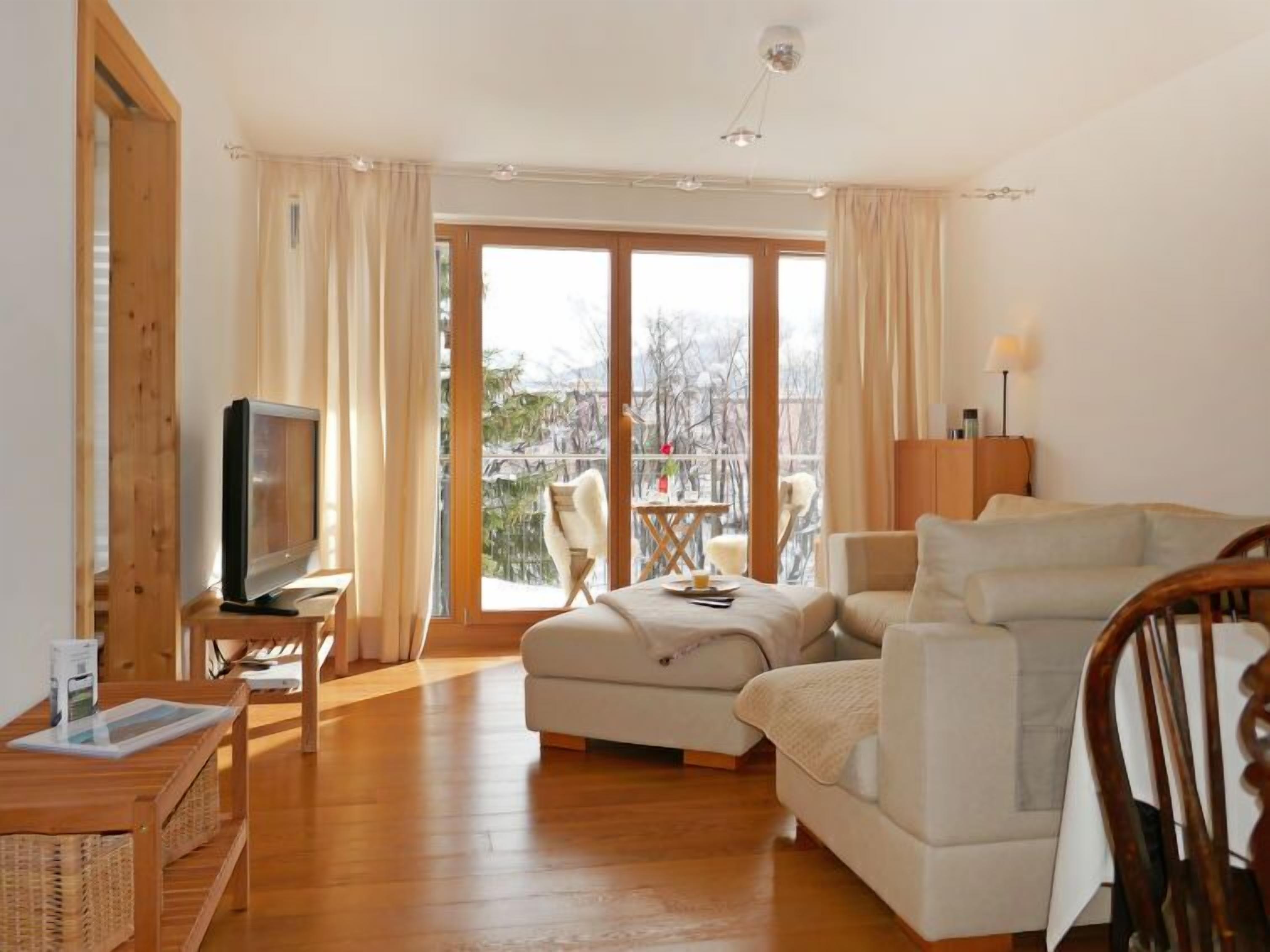 Un salon confortable avec une télévision, un canapé, une table basse et un balcon offrant une vue agréable.