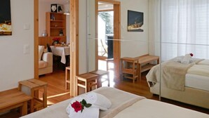 Ein Hotelzimmer mit einem Bett, einem kleinen Schreibtisch, einem Sessel, einer Couch und einer Essecke mit Tisch und Stühlen.