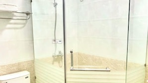 A glass-enclosed shower stall with a handheld showerhead, a toilet, and a towel rack. - Nhu Y Hotel (Ho Chi Minh City)