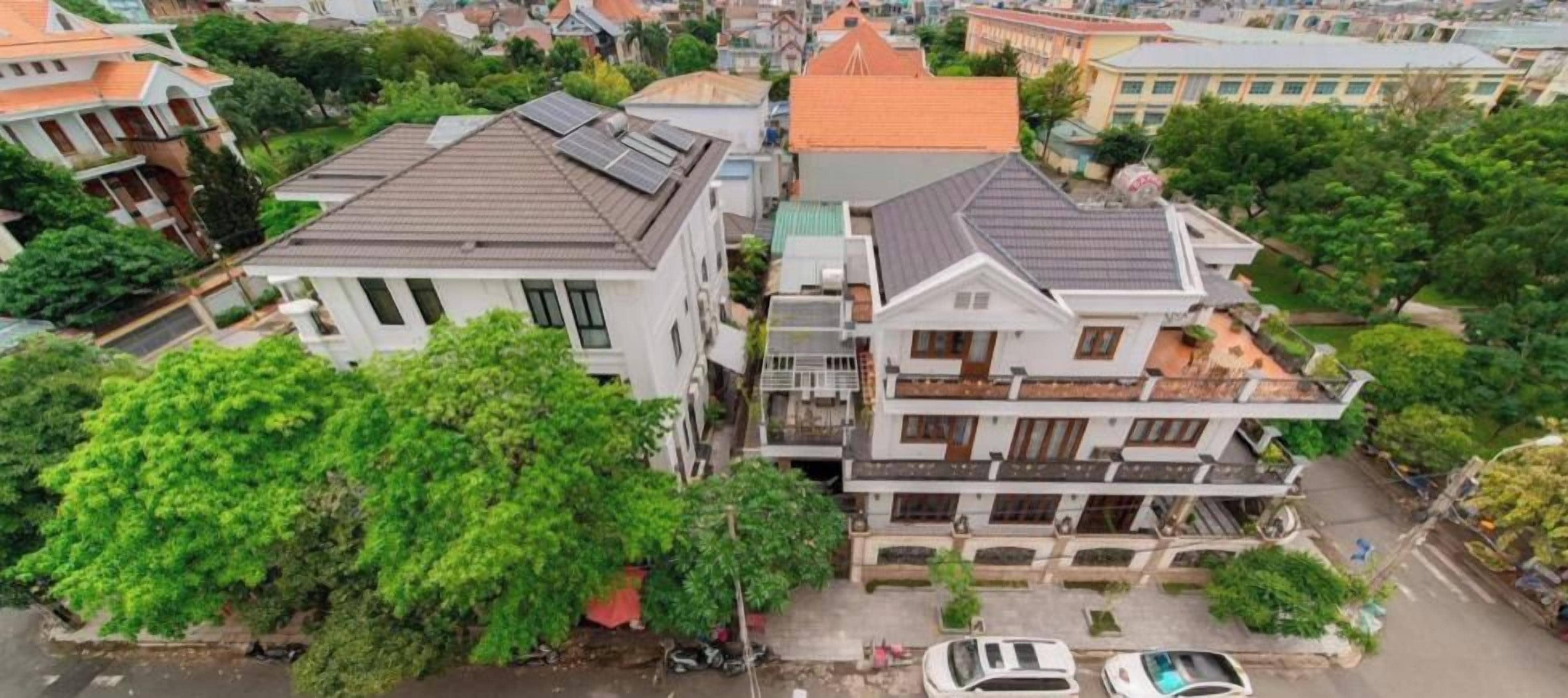 A multi-story residential building with a central courtyard, surrounded by trees and adjacent to a body of water.