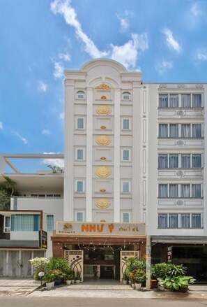 A hotel with a central entrance, multiple floors, and a signboard.