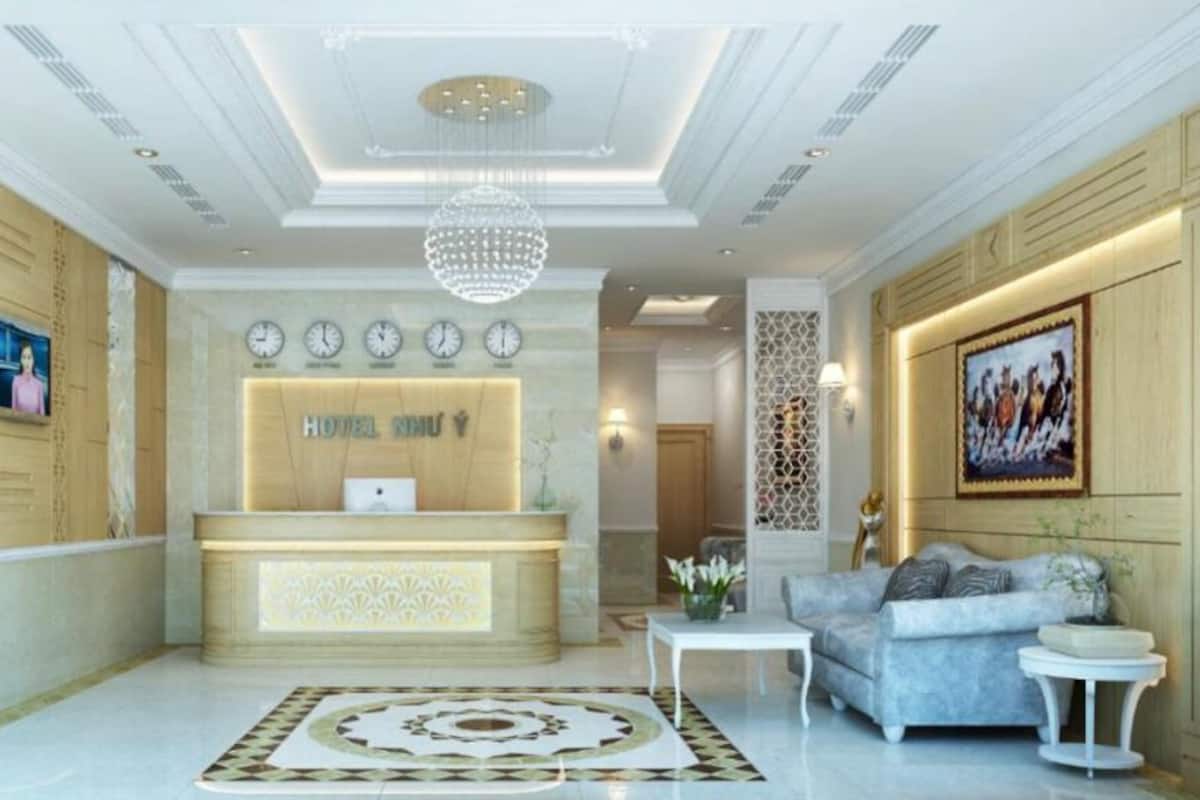 Eine Hotelhalle mit einer Rezeption, Uhren, einer Chandelier, einer Couch und einem gemusterten Teppich.