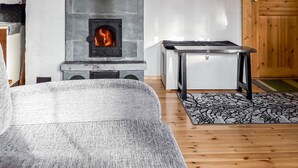 A modern living room with a stone fireplace, a sofa, a small table, and a wooden floor. - Kesäniitty by Interhome (Ähtäri)
