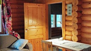 A log cabin interior with a wooden door, a sofa, a table, and a window. - Kesäniitty by Interhome (Ähtäri)