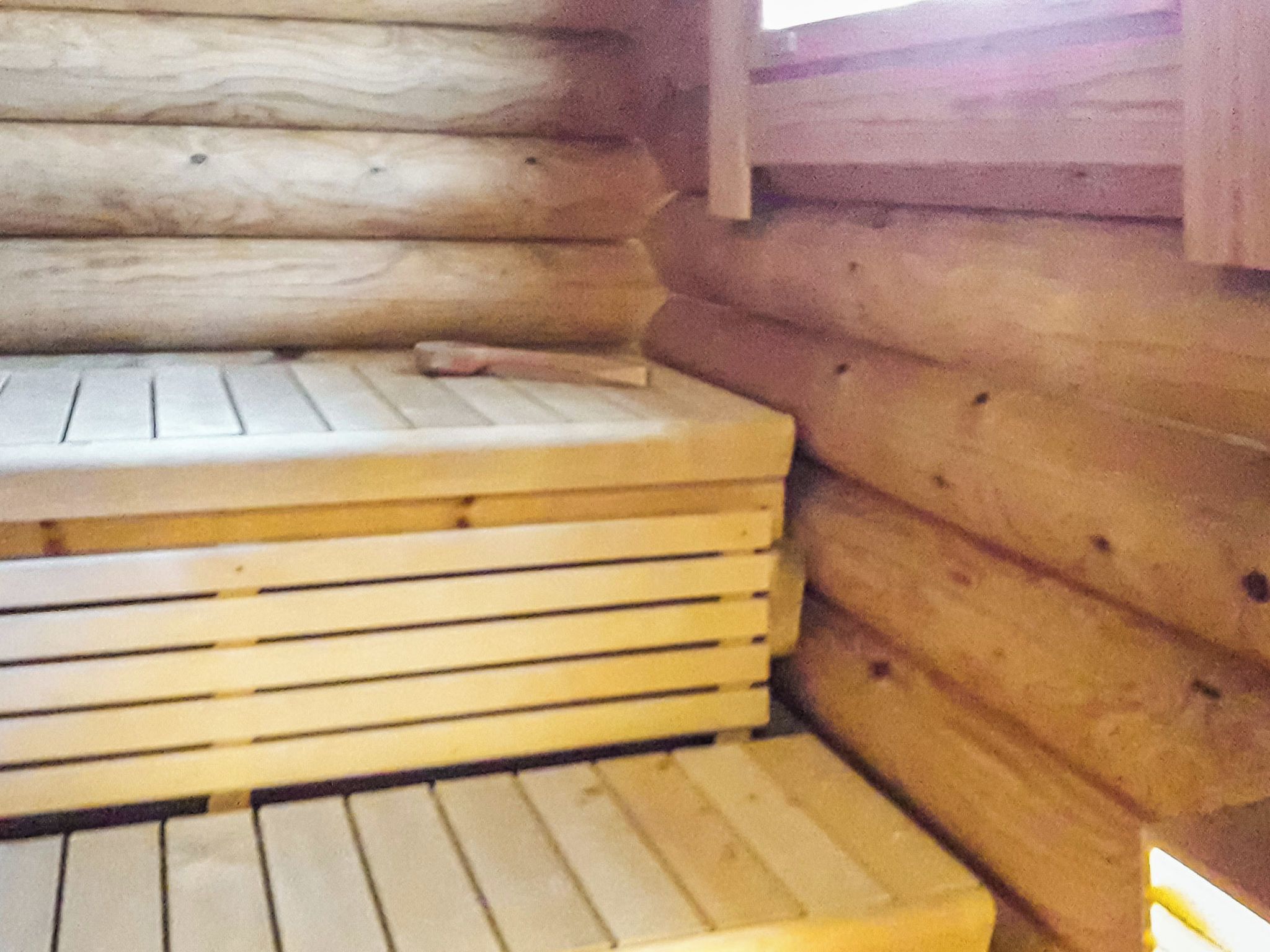 A wooden cabin interior with a bench and a fireplace.