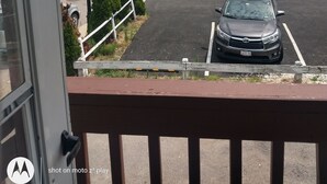 Un estacionamiento con varios autos, un edificio con el letrero 'Shops Inn' y un camión grande.