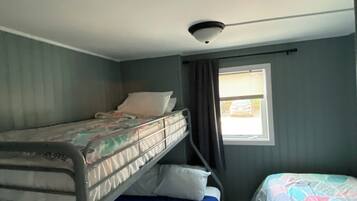 A room with bunk beds, a window with curtains, and a ceiling fan.