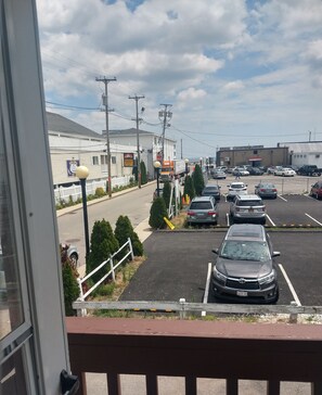 Un estacionamiento con varios autos, un edificio con el letrero 'Shops Inn' y un camión grande.
