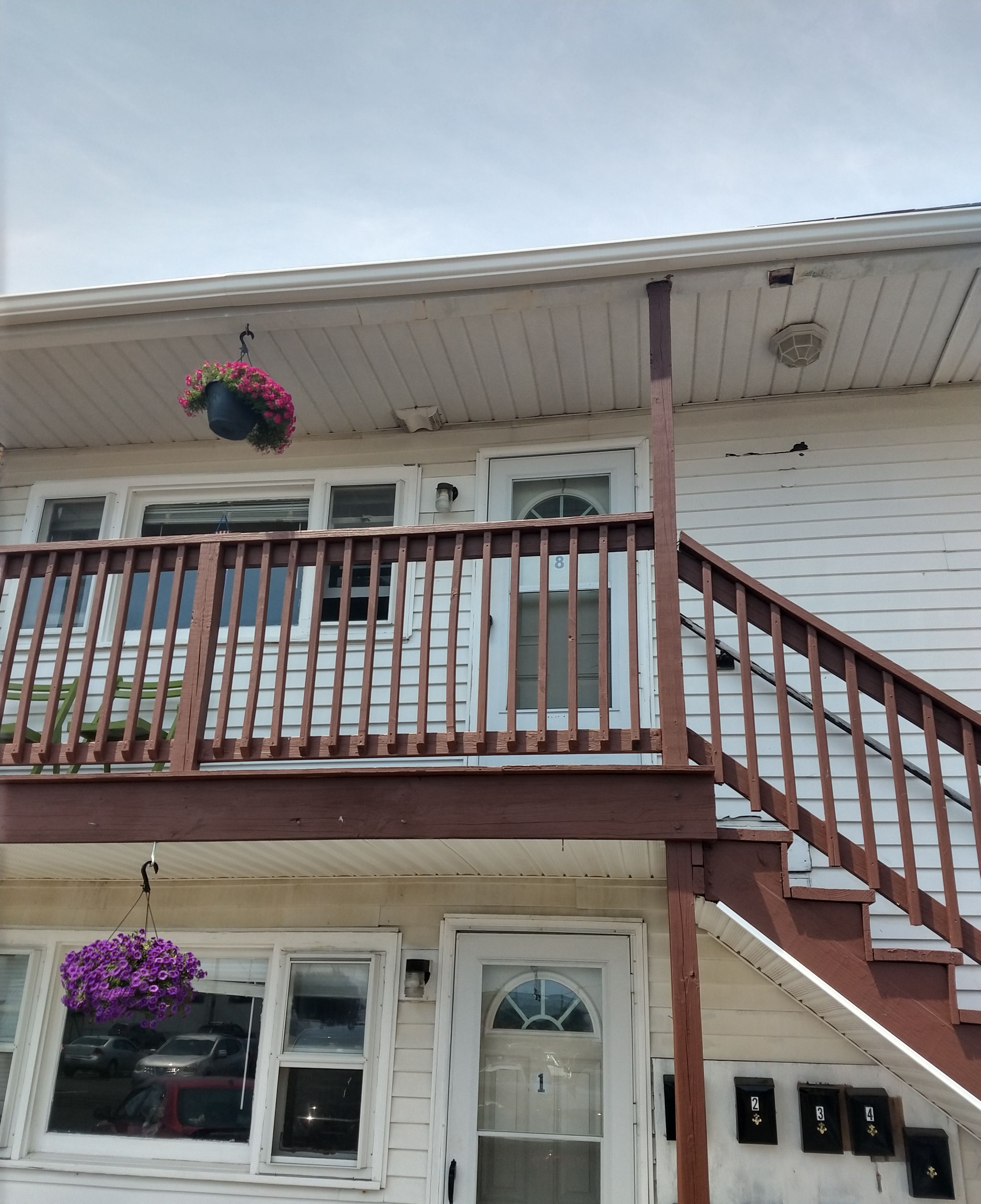 Une maison à deux étages avec un balcon en bois et un escalier.
