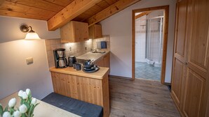 Eine kleine Küche mit Holzschränken, einer Kaffeemaschine und einem Spülbecken.