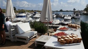 A marina with boats, lounge chairs, and a buffet table with food. - AP FLAMENC, Ideal house for your holidays near the sea, free wifi, air conditioning optional, pets allowed, dog’s beach (Delta de l'Ebre)