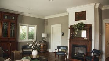 A spacious living room with a fireplace, wooden furniture, and a large window.