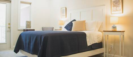 A bedroom with a bed, bedside tables, and wall-mounted lamps.