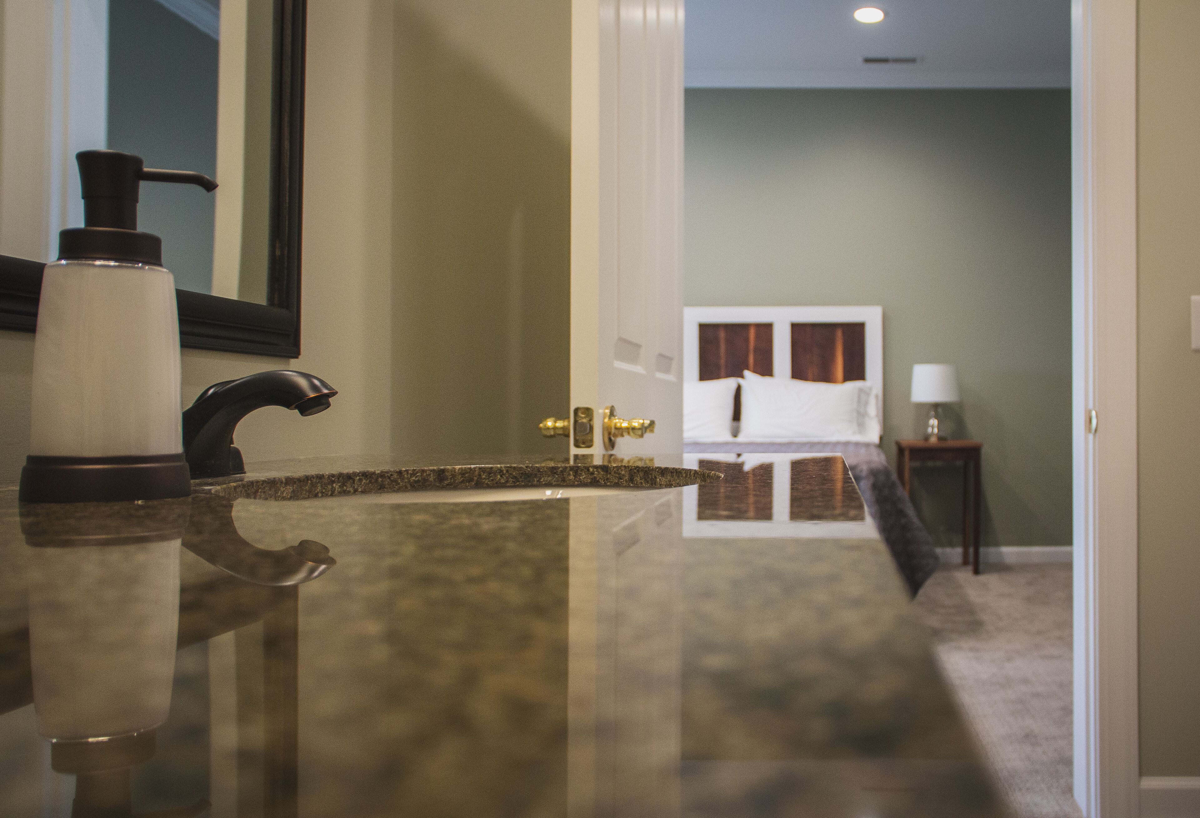 A bathroom with a marble countertop, a black faucet, and a white bottle.