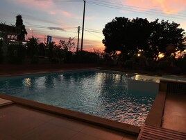 Une piscine dotée d’une terrasse carrelée, entourée d’arbres et d’une clôture.