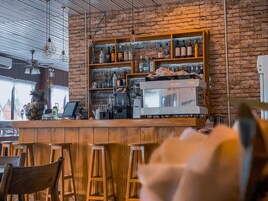 Un espace bar avec des tabourets en bois, une machine à café et des étagères remplies de bouteilles.