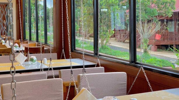 Interior de restaurante com assentos pendurados e amplas janelas que oferecem vista para o exterior.