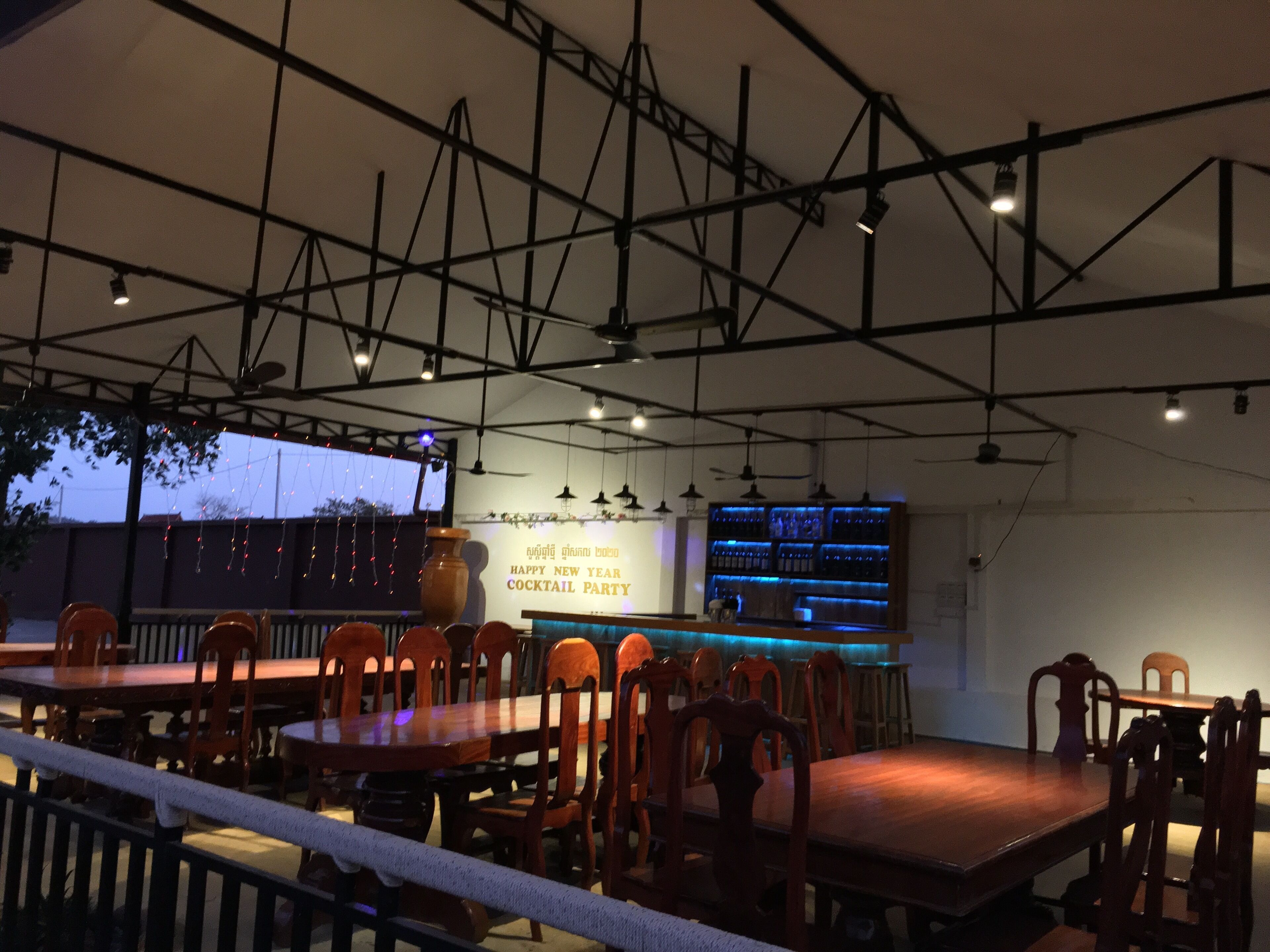 A restaurant with wooden tables and chairs, a bar area, and a ceiling with exposed beams.