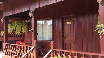 A wooden building with a porch, a door labeled "V-011", and a potted plant in the foreground.