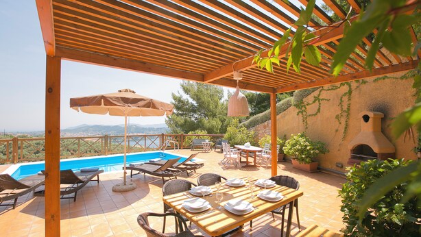 A covered outdoor area with a pool, lounge chairs, and a table set for dining. - Europa,2br,2bth Villa With Private Pool And Stunning Sea Views (Skiathos Island)