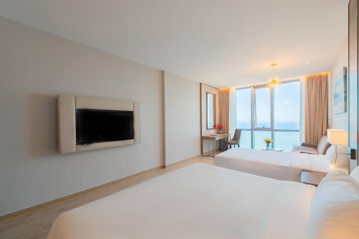 Een hotelkamer met twee bedden, een televisie, een bureau met een stoel en een groot raam met uitzicht.