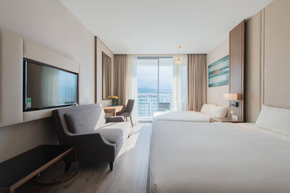 Hotelkamer met een groot bed, een bureau, een stoel, een televisie en uitzicht op de stad.