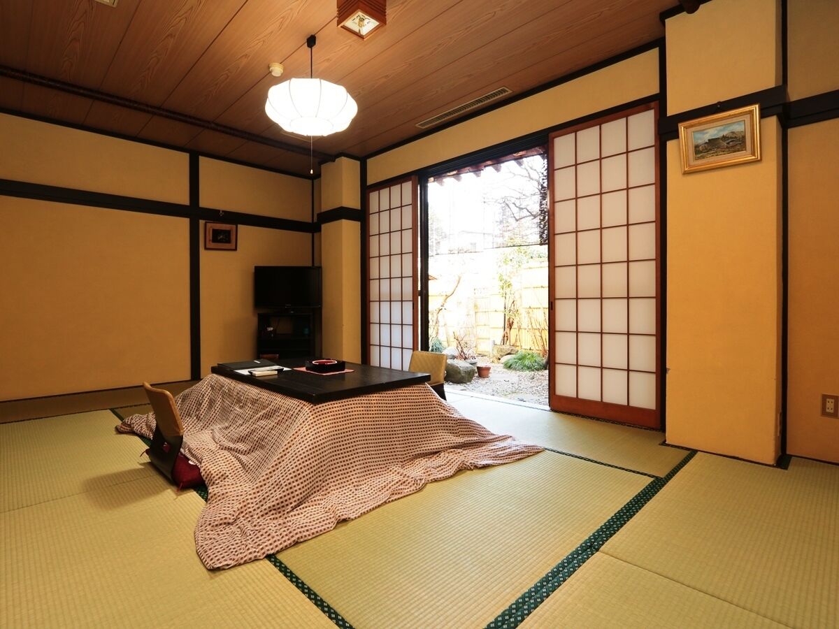 A traditional Japanese room with tatami flooring, a low table, and sliding doors.