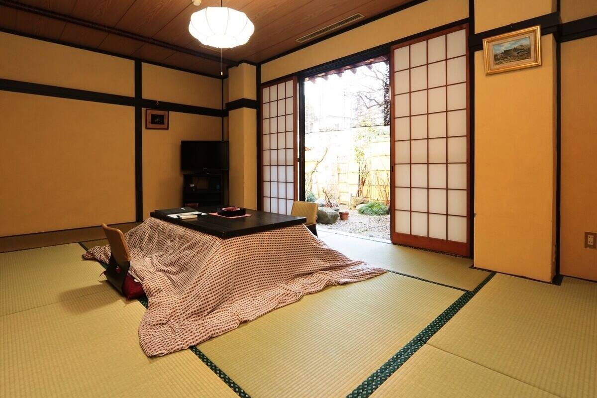 Une pièce de style japonais traditionnel, avec un sol recouvert de tatamis, une table basse et des portes coulissantes.