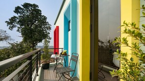 A balcony with a table and chairs, a potted plant, and a view of the landscape. - Viryla Boutique Hotel (Vientiane)