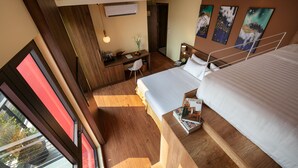 A hotel room with a large bed, a desk with a chair, a small table with a vase, and artwork on the walls. - Viryla Boutique Hotel (Vientiane)