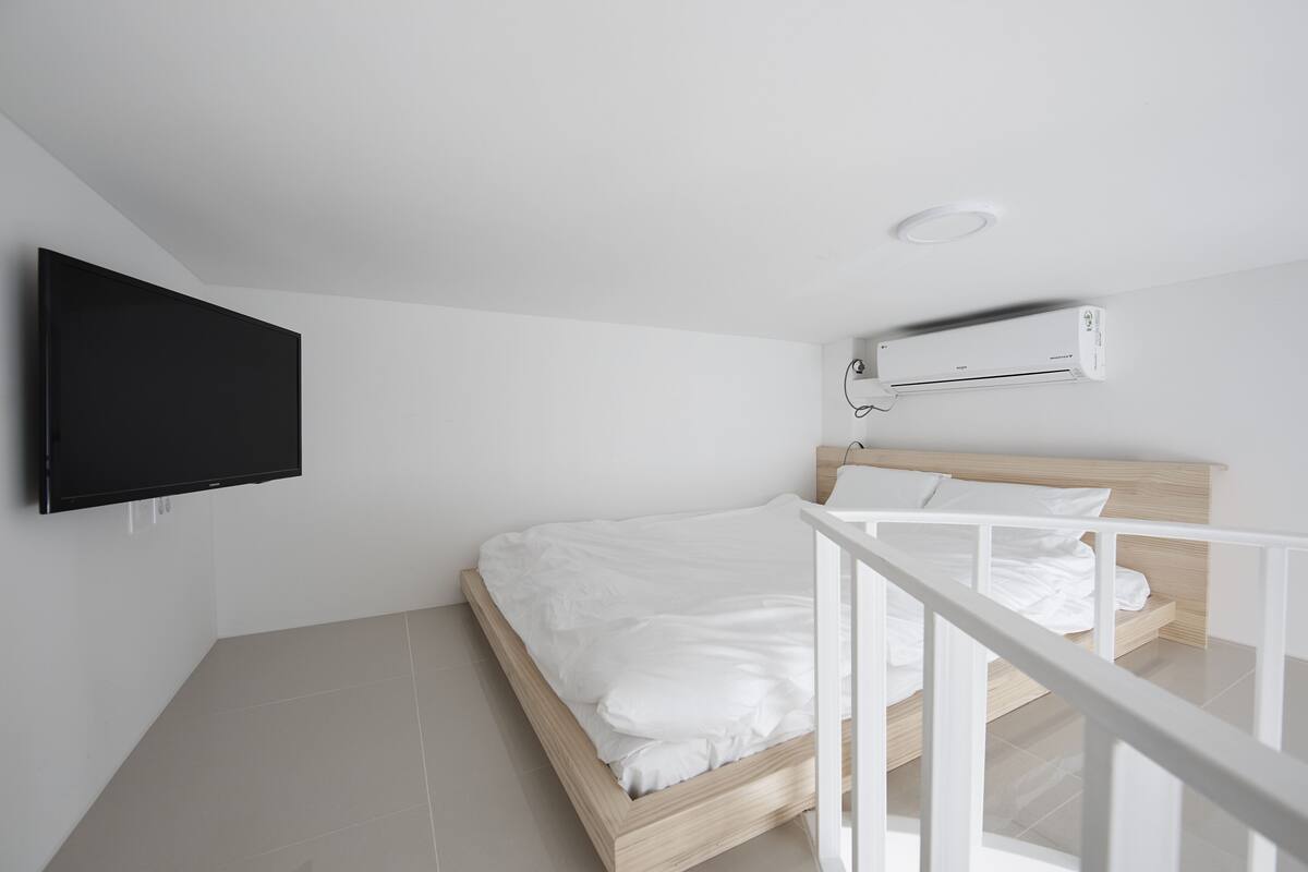 Une chambre à coucher avec un lit, un téléviseur fixé au mur et un appareil de climatisation.
