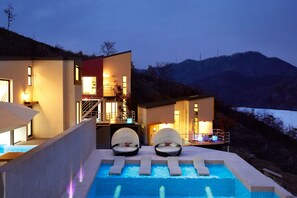 Un hotel moderno con piscina, dos camas de spa y vista a la montaña.