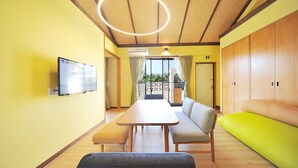A room with a wooden table, bench, sofa, and a television mounted on the wall. - SUMU Villa (Nago)