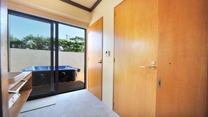 A room with a sliding glass door leading to a balcony, a wooden door, and a small window. - SUMU Villa (Nago)