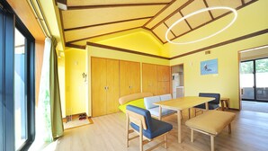 A bright room with wooden floors, a table, chairs, and a bench. - SUMU Villa (Nago)