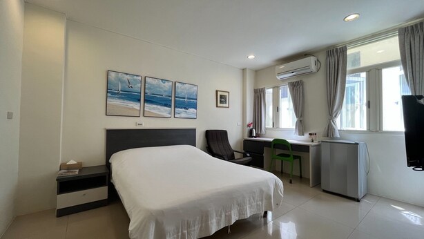 Quarto de hotel com cama, escrivaninha, cadeira e ar condicionado.
