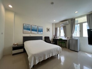 Habitación de hotel con cama, escritorio, silla y equipo de aire acondicionado.