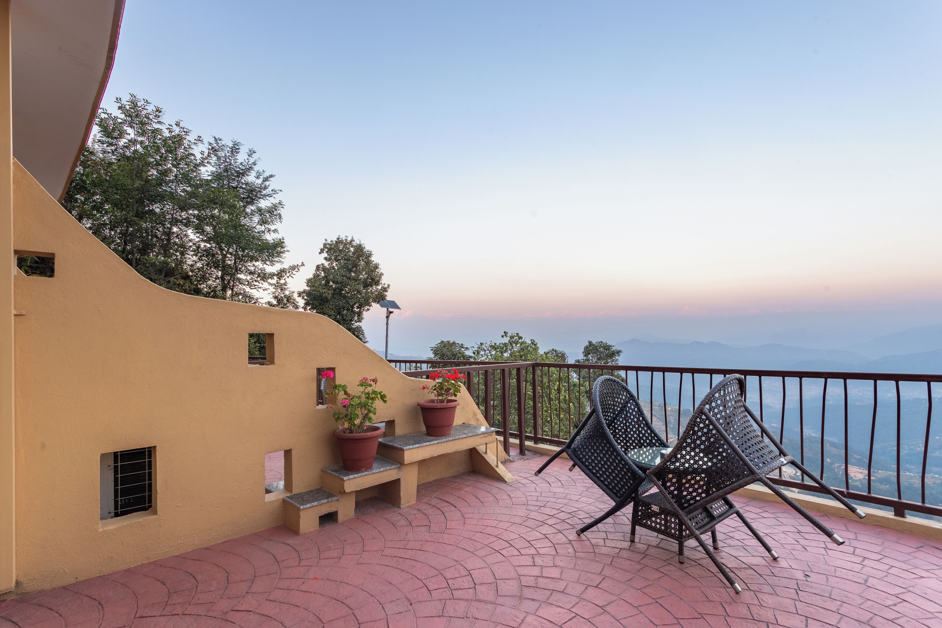A balcony with two chairs, a bench, and potted plants.