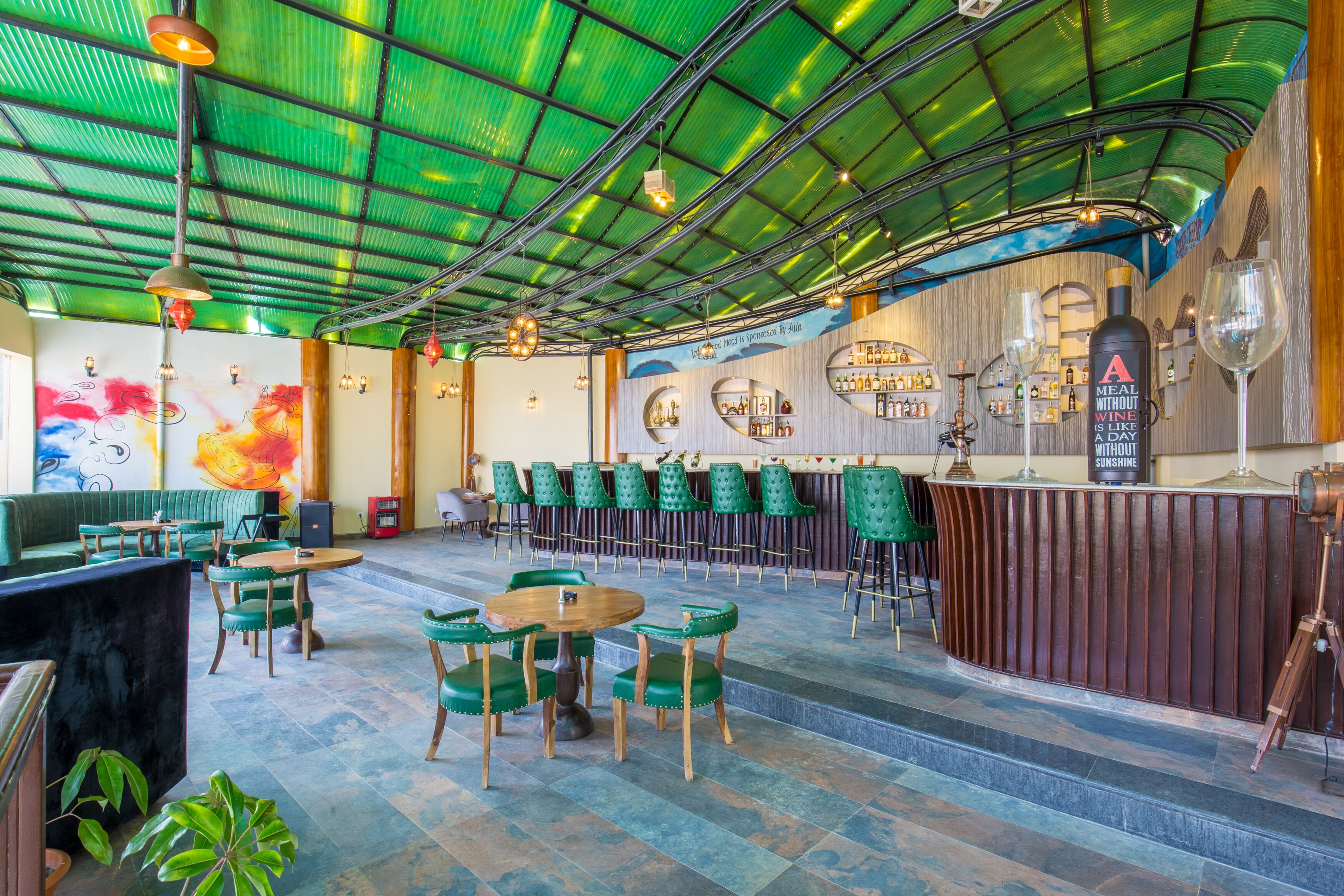 Ein Restaurant mit grünen Stühlen, einer Bar und einem Wandgemälde.