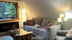 A cozy living room with a sofa, two armchairs, a coffee table, and a TV.