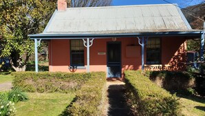 A small building with a corrugated metal roof, a front door, and a sign that reads "REDRUTH". - Redruth - 2 bedroom cottage situated in wandiligong (WANDILIGONG)