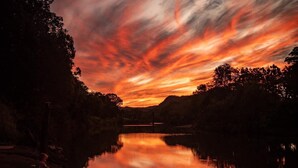Un coucher de soleil sur un lac paisible, avec la silhouette d’une personne sur la rive.