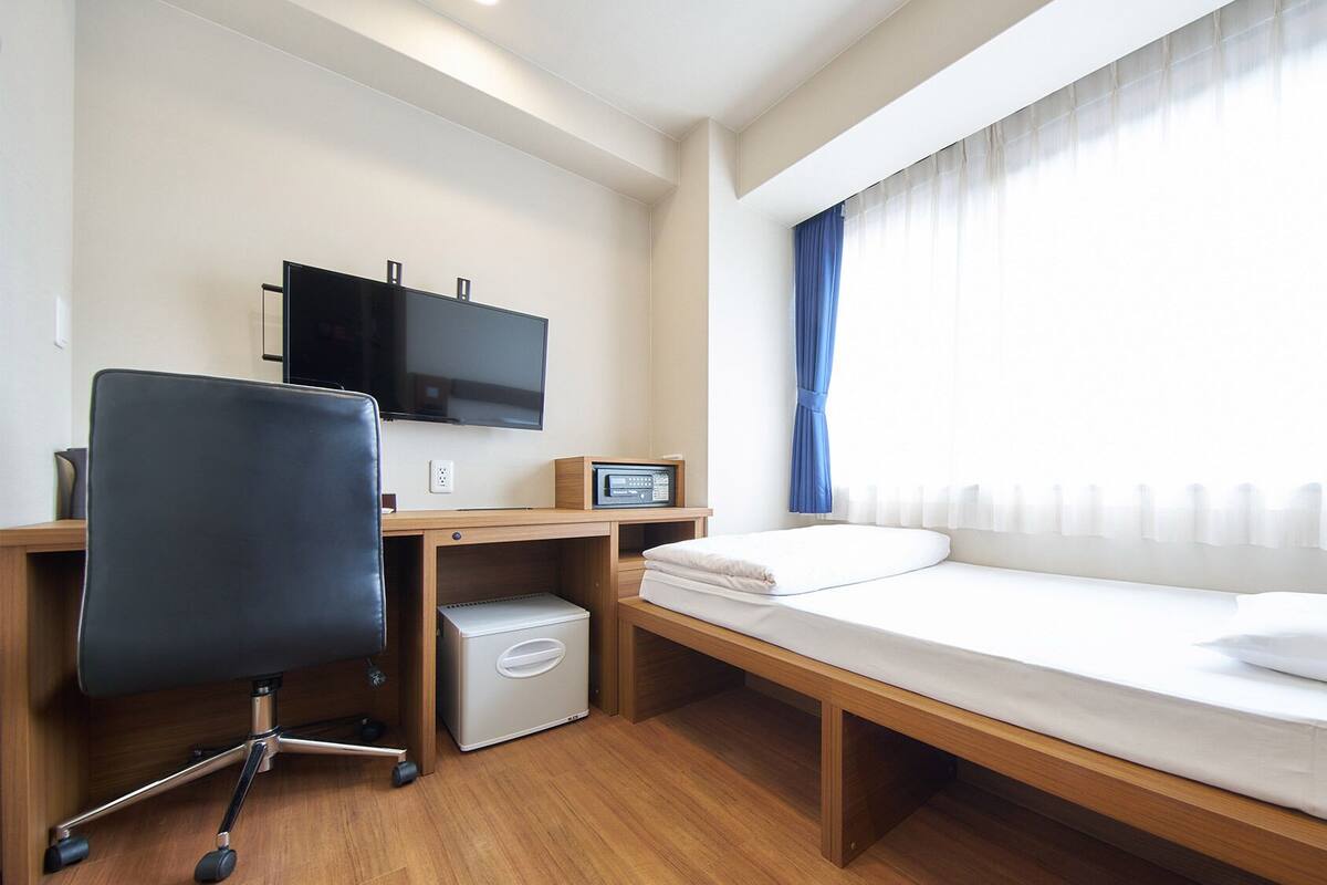 Una habitación de hotel con una cama, un escritorio con computadora, una silla y televisión.