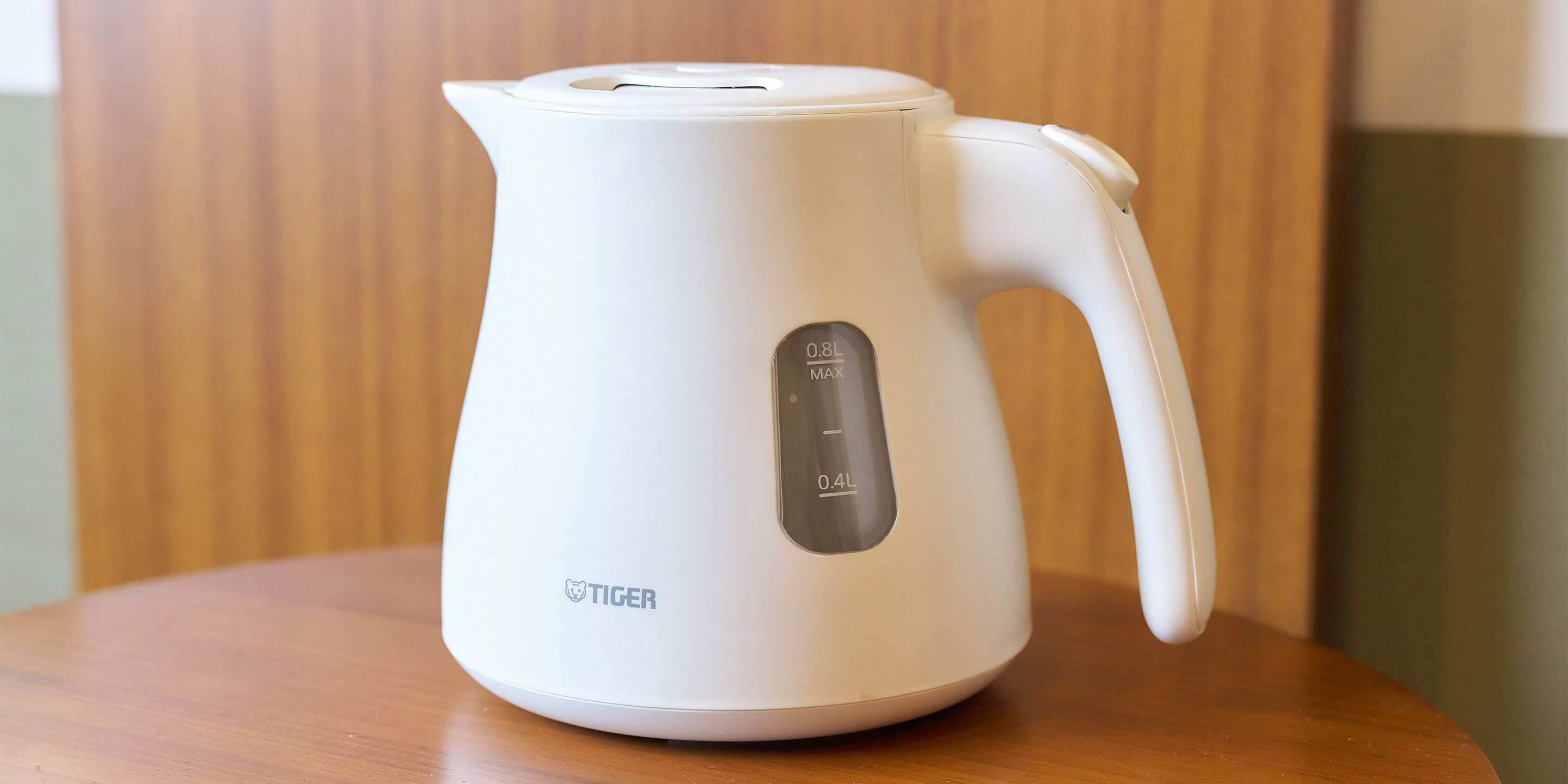 A white electric kettle with a digital display on a wooden table.