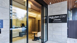 A modern urban hotel entrance with a reception desk, a seating area, and a sign indicating the hotel name 'Rakuten Stay Urban'. - Rakuten STAY URBAN Shijo Kawaramachi (Kyoto)